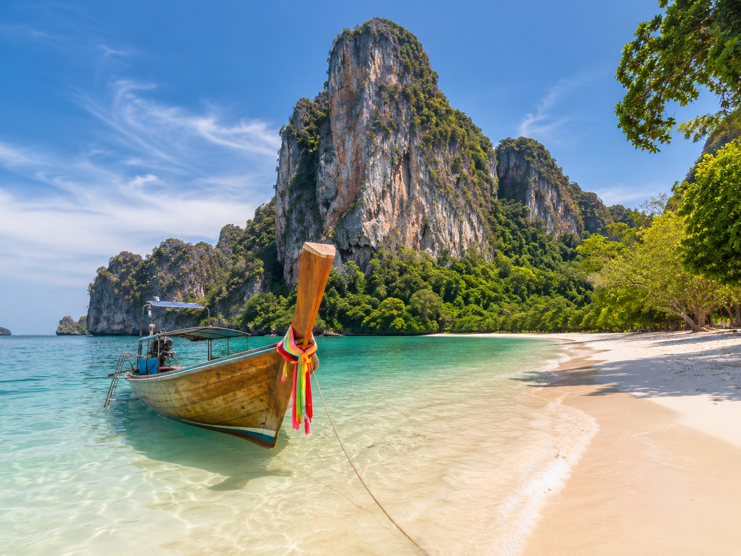 Longtailbåt vid tropisk strand i Thailand